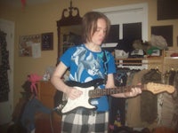 a girl playing an electric guitar in a room